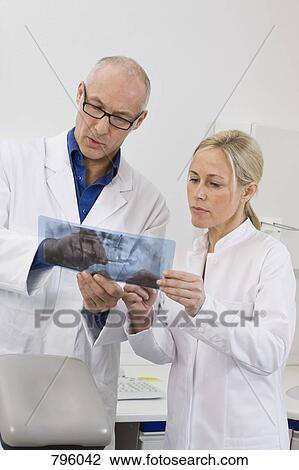 Dentist and dental assistant looking at an x-ray View Large Photo Image Stock Image - Dentist and dental assistant looking at an x-ray. Fotosearch