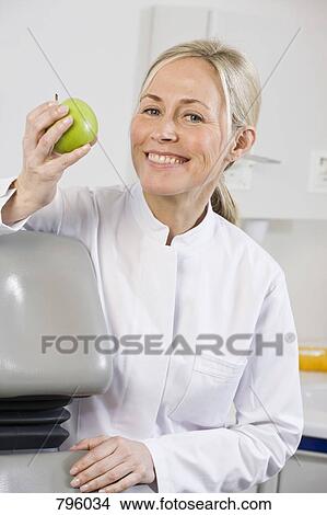 Portrait of a dental assistant holding an apple View Large Photo Image Picture - Portrait of a dental assistant holding an apple. Fotosearch