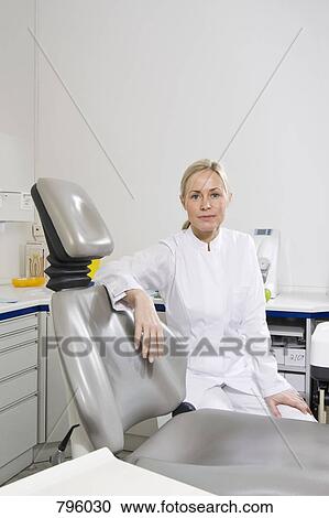 Portrait of a dental assistant sitting behind a dental chair View Large Photo Image Stock Image - Portrait of a dental assistant sitting behind a dental chair. Fotosearch