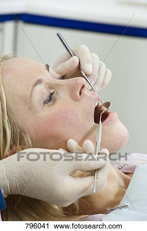 Side view of a dentist inspecting a woman's mouth View Large Photo Image Stock Image - Side view of a dentist inspecting a woman's mouth. Fotosearch