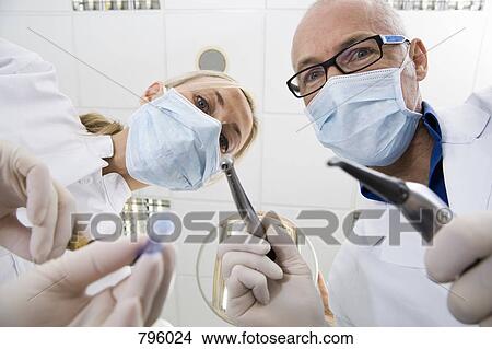 View from below of a dentist and an assistant holding View Large Photo Image Picture - View from below of a dentist and an assistant holding . Fotosearch
