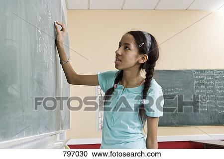 A girl writing on a blackboard in a classroom View Large Photo Image Stock Image - A girl writing on a blackboard in a classroom. Fotosearch