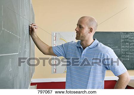 A male teacher writing on a blackboard View Large Photo Image Stock Photo - A male teacher writing on a blackboard. Fotosearch