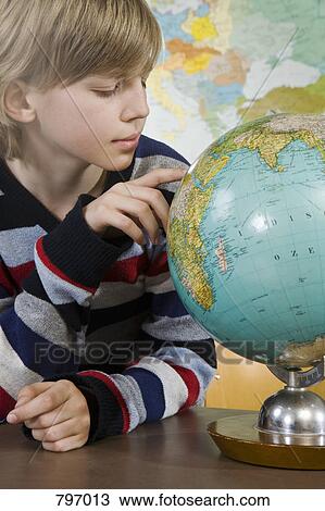 Stock Image - A schoolboy looking at a globe. Fotosearch
