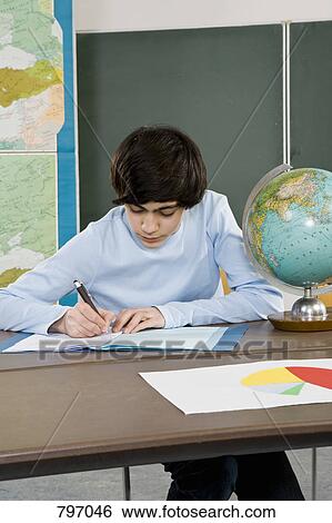 A schoolboy working at a desk View Large Photo Image Stock Photograph - A schoolboy working at a desk. Fotosearch