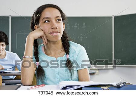 A schoolgirl sitting at a desk View Large Photo Image Stock Photography - A schoolgirl sitting at a desk. Fotosearch