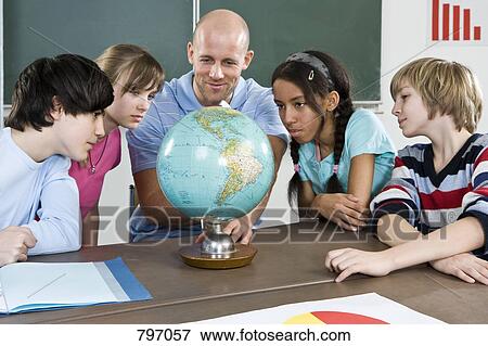 Stock Photo - A teacher and students looking at a globe. Fotosearch