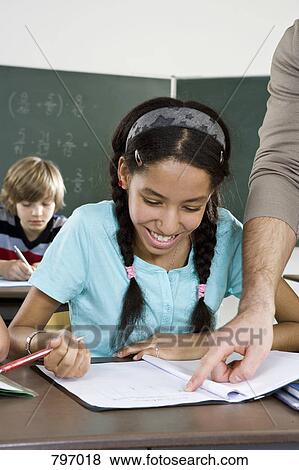 A teacher assisting a schoolgirl in a classroom View Large Photo Image Stock Photo - A teacher assisting a schoolgirl in a classroom. Fotosearch