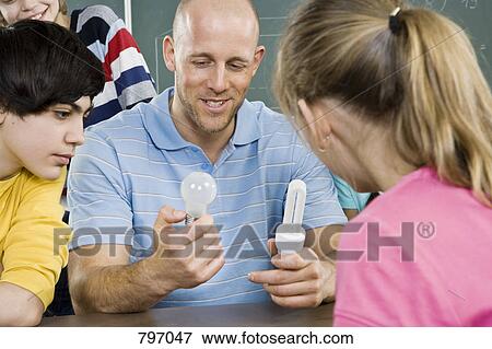 A teacher comparing two types of light bulbs with students View Large Photo Image Stock Photo - A teacher comparing two types of light bulbs with students. Fotosearch