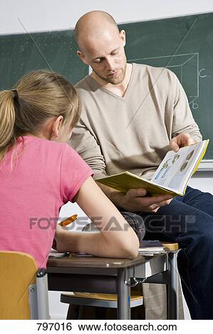A teacher looking at a book with a student View Large Photo Image Stock Photograph - A teacher looking at a book with a student. Fotosearch