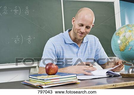 A teacher sitting at a desk View Large Photo Image Stock Image - A teacher sitting at a desk. Fotosearch
