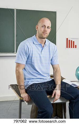 A teacher sitting on a desk View Large Photo Image Stock Image - A teacher sitting on a desk. Fotosearch