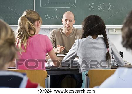 Picture - A teacher talking to students in a classroom. Fotosearch