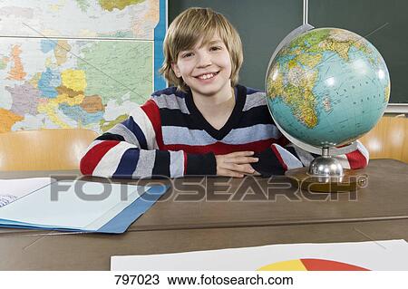 Portrait of a schoolboy sitting near a globe View Large Photo Image Stock Image - Portrait of a schoolboy sitting near a globe. Fotosearch