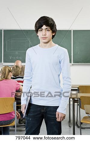 Portrait of a schoolboy standing in a classroom View Large Photo Image Picture - Portrait of a schoolboy standing in a classroom. Fotosearch