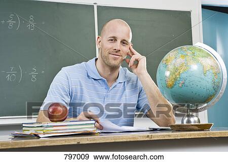 Portrait of a teacher sitting at a desk View Large Photo Image Stock Photo - Portrait of a teacher sitting at a desk. Fotosearch