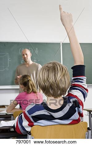 Rear view of a boy raising his hand in a classroom View Large Photo Image Stock Image - Rear view of a boy raising his hand in a classroom. Fotosearch