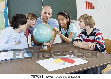 School students and a teacher looking at a globe View Large Photo Image Stock Image - School students and a teacher looking at a globe. Fotosearch