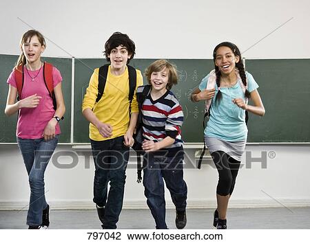 Stock Image - School students running together in a classroom. Fotosearch