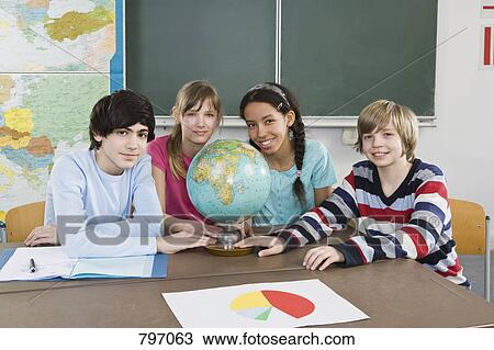 School students sitting at a table with a world globe View Large Photo Image Stock Image - School students sitting at a table with a world globe. Fotosearch