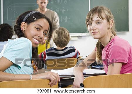 Two schoolgirls sitting in a classroom View Large Photo Image Stock Image - Two schoolgirls sitting in a classroom. Fotosearch