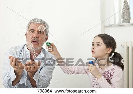 A grandfather and granddaughter playing with soap bubbles View Large Photo Image Picture - A grandfather and granddaughter playing with soap bubbles. Fotosearch