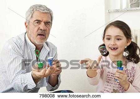 A grandfather and granddaughter playing with soap bubbles View Large Photo Image Stock Photo - A grandfather and granddaughter playing with soap bubbles. Fotosearch