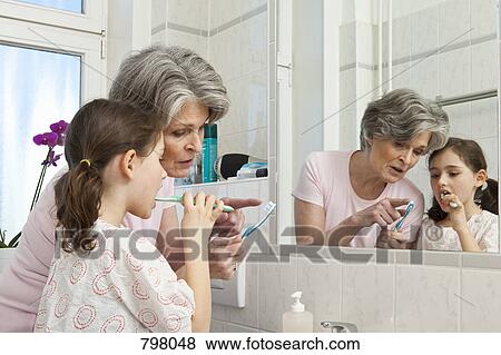 A grandmother teaching her granddaughter how to brush teeth View Large Photo Image Stock Photo - A grandmother teaching her granddaughter how to brush teeth. Fotosearch