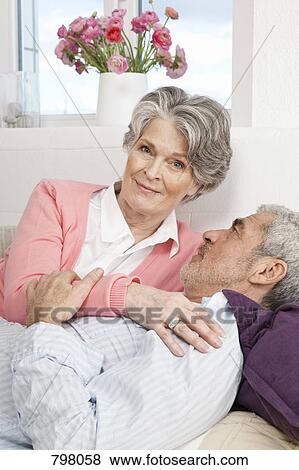 Stock Photo - A senior man and a senior woman lying on a couch together. Fotosearch