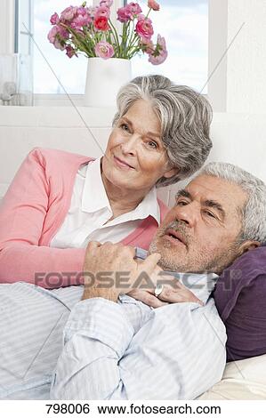 A senior man and a senior woman lying on a couch together View Large Photo Image Stock Photograph - A senior man and a senior woman lying on a couch together. Fotosearch