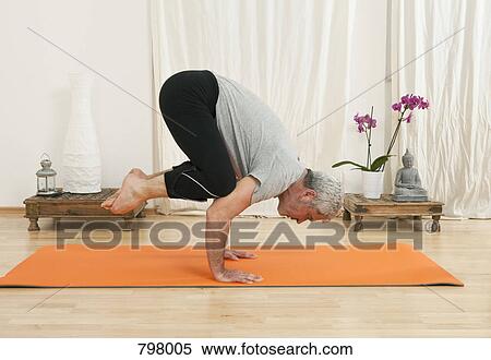Stock Photography - A senior man doing yoga, crow pose. Fotosearch