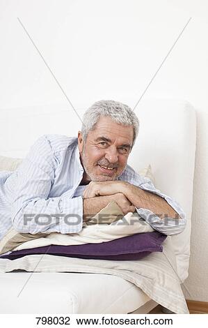 A senior man lying on a couch View Large Photo Image Stock Image - A senior man lying on a couch. Fotosearch
