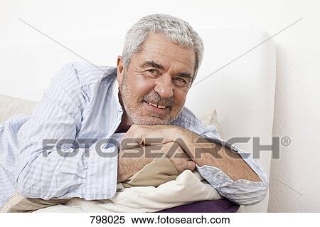 Stock Photography - A senior man lying on a couch. Fotosearch