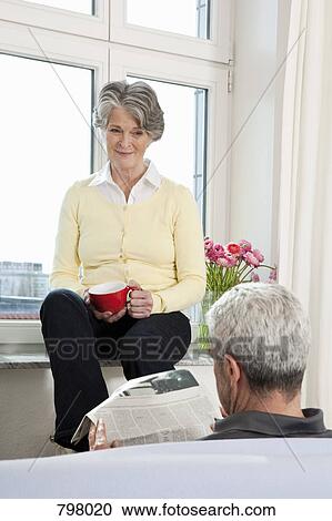 A senior man reading a newspaper and his wife watching him View Large Photo Image Stock Image - A senior man reading a newspaper and his wife watching him. Fotosearch