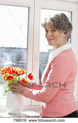 A senior woman arranging flowers in a vase View Large Photo Image Stock Photo - A senior woman arranging flowers in a vase. Fotosearch