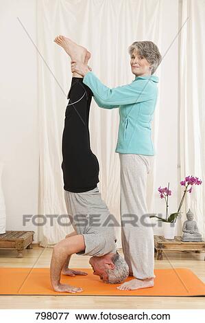 A senior woman helping a senior man doing a headstand View Large Photo Image Stock Photo - A senior woman helping a senior man doing a headstand. Fotosearch