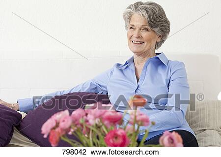 Stock Image - A senior woman relaxing in a living room. Fotosearch