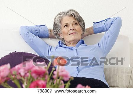 Stock Photo - A senior woman relaxing in a living room. Fotosearch