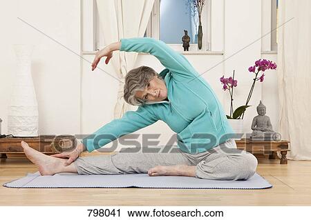 Stock Image - A senior woman stretching in a yoga studio. Fotosearch