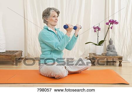 A senior woman working out with hand weights in a yoga studio View Large Photo Image Stock Photo - A senior woman working out with hand weights in a yoga studio. Fotosearch