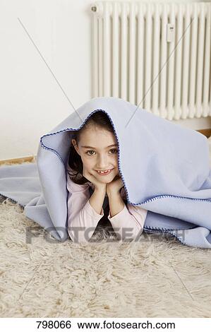 Stock Photograph - A young girl hiding under a blanket. Fotosearch