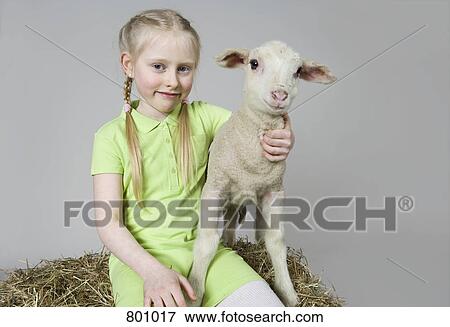 Stock Photo - A girl with a white lamb, studio shot. Fotosearch