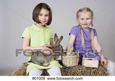 Stock Photo - Two girls with a rabbit and a duckling in a basket. Fotosearch