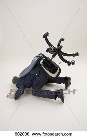 Stock Photo - A businessman in a turned over chair. Fotosearch