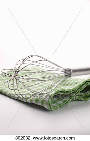 Stock Image - A wire whisk and checkered dish towel. Fotosearch