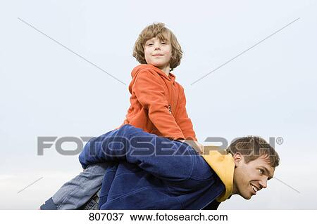 A man carrying a boy on his back View Large Photo Image Stock Photo - A man carrying a boy on his back. Fotosearch