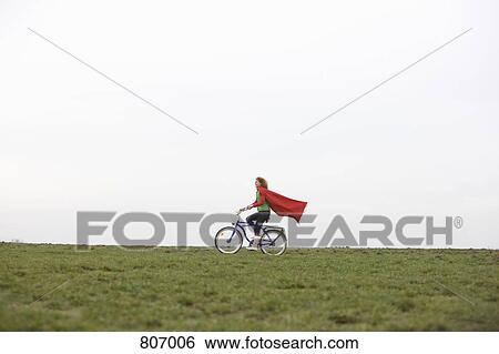 A woman riding a bike through a park View Large Photo Image Stock Photograph - A woman riding a bike through a park. Fotosearch