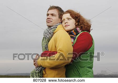 Stock Photo - A young couple dressed in warm clothing embracing. Fotosearch