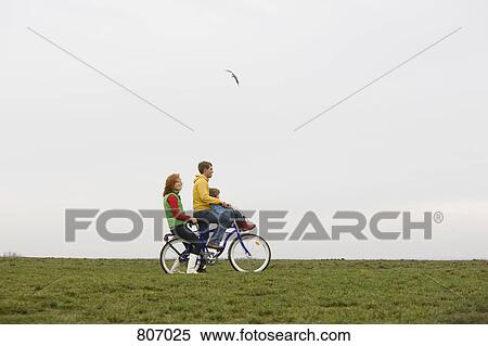 Stock Photography - A young family on a bike together. Fotosearch