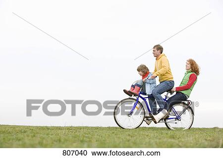 Stock Image - A young family riding on a bike together. Fotosearch
